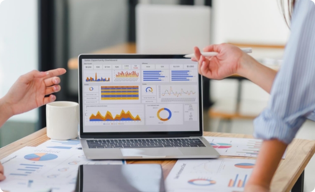 Two professionals analyzing medical coding performance metrics on a laptop dashboard—featuring graphs, charts, and data visualization for AI-driven healthcare analytics.